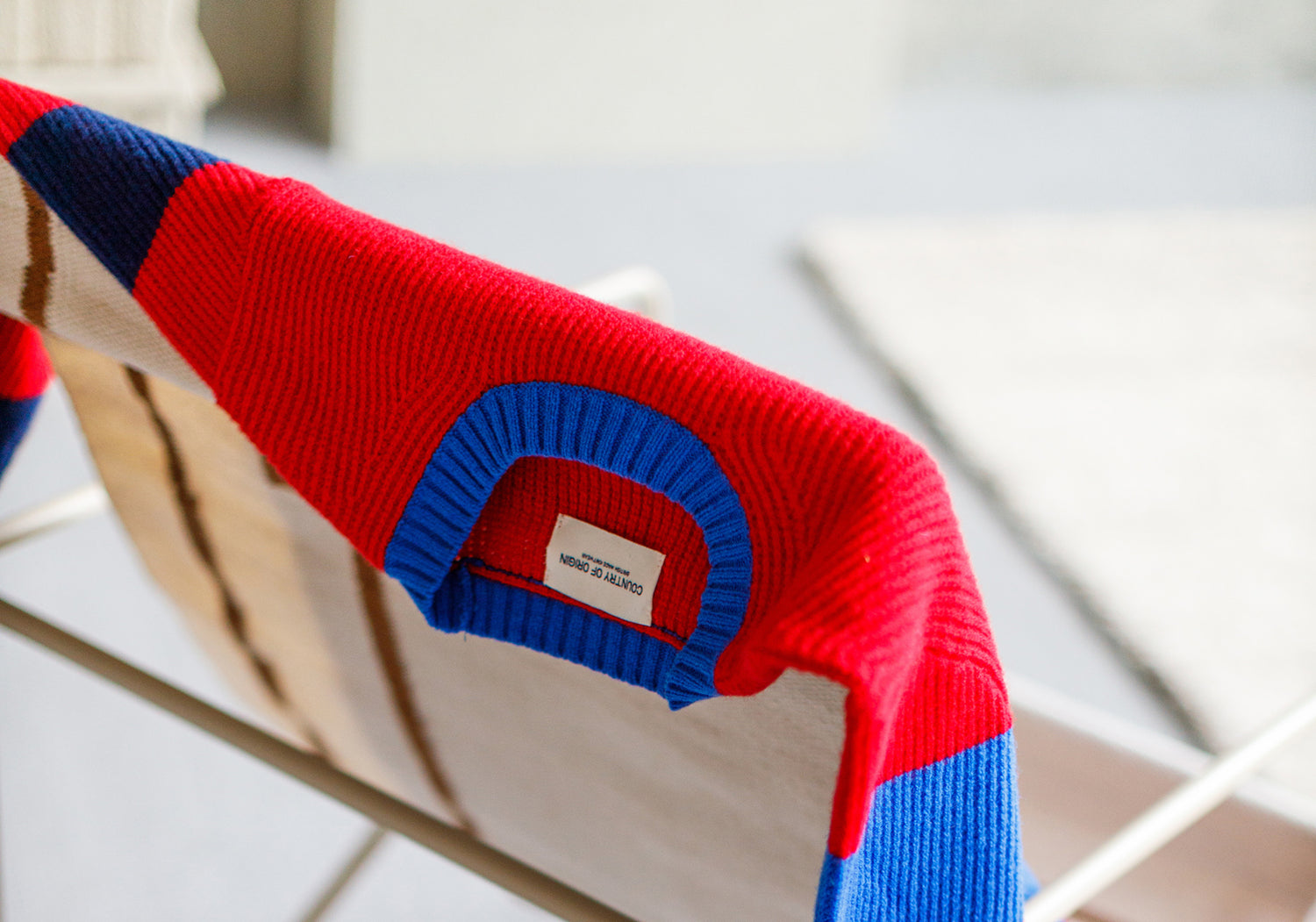 A colorful knit sweater draped over the back of a chair.