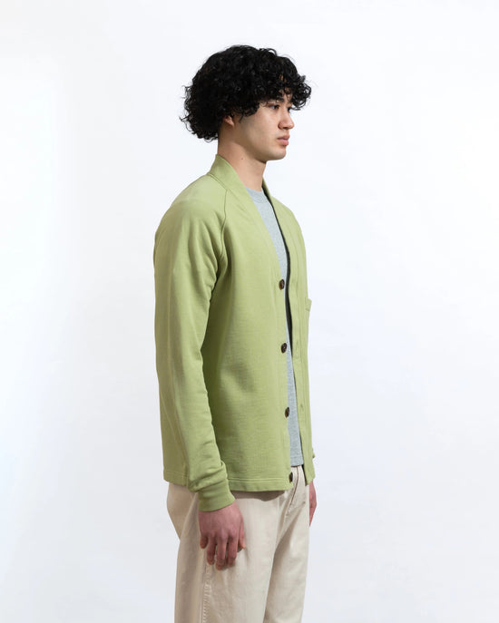 A person wears a green cardigan over a grey t-shirt